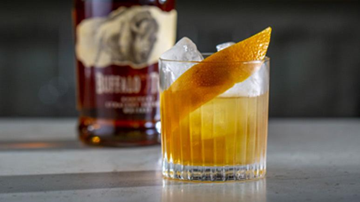 Buffalo Trace bourbon next to an Old Fashioned cocktail with orange peel garnish